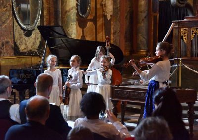 Adventní koncert ZUŠ 7.12.2019 - Klementinum. Pohled na pět zpívajících a hrajících děvčat z lidového souboru.