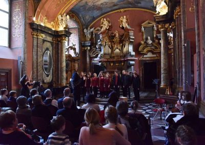 Adventní koncert ZUŠ 7.12.2019 - Klementinum. Pohled na publikum, zpívající sbor a paní sbormistryni M. Džunevu.