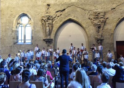 Závěrečný koncert Pueri gaudentes 24.6.2019 - Anežský klášter. Pohled na publikum, pana sbormistra J. Kyjovského a zpívající koncertní sbor.