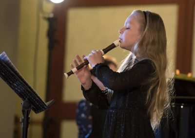 Dechový koncert, Profesní dům MFF, žačka hrající na zobcovou flétnu.
