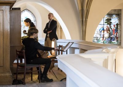 Varhanní koncert, kostel sv. Michala v Jirchářích, žačka hrající na varhany a pan učitel.