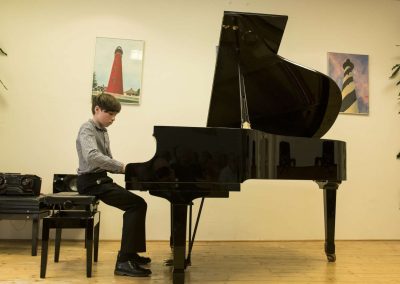 Školní absolventský koncert, komorní sál ZUŠ Šimáčkova, žák hrající na klavír.