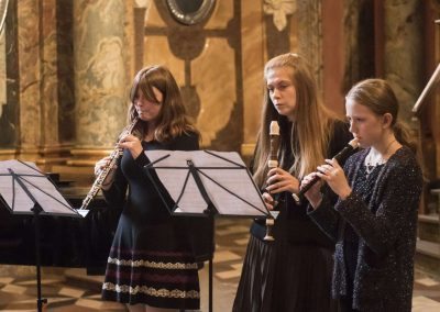 Adventní koncert v Klementinu, 10.12.2022, žáci s paní učitelkou hrající na zobcové flétny.