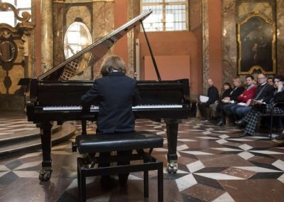 Adventní koncert v Klementinu, 10.12.2022, žák hrající na klavír.