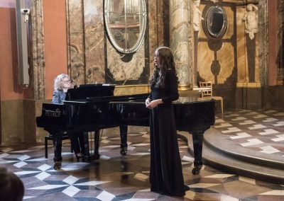 Adventní koncert v Klementinu, 10.12.2022, zpívající žákyně a paní učitelka doprovázející n a klavír.