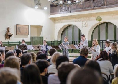 Adventní koncert v Hlaholu, 17.12.2022, žáci a paní učitelka hrající na zobcové flétny.
