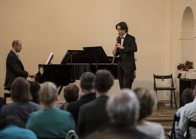 I. absolventský koncert, Atrium na Žižkově, 10.5.2023, žák hrající na klavír a pan učitel doprovázející na klavír