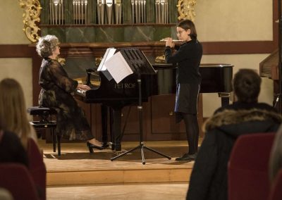 Dechový koncert, Profesní dům MFF, 27.2.2023, žákyně hrající na flétnu a paní učitelka