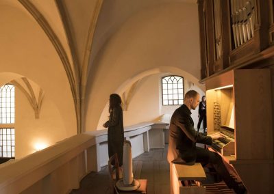 Varhanní koncert, kostel sv. Michala, 26.4.2023, zpívající žákyně a pan učitel hrající na varhany
