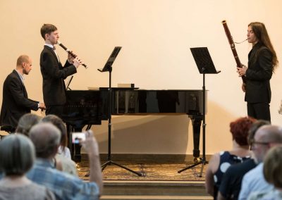 II. absolventský koncert, Atrium na Žižkově, 1.6.2023, žák hrající na flétnu, žák hrající na fagot a pan učitel doprovázející na klavír