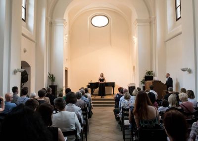 II. absolventský koncert, Atrium na Žižkově, 1.6.2023, zpívající žákyně a pan učitel hrající na varhany